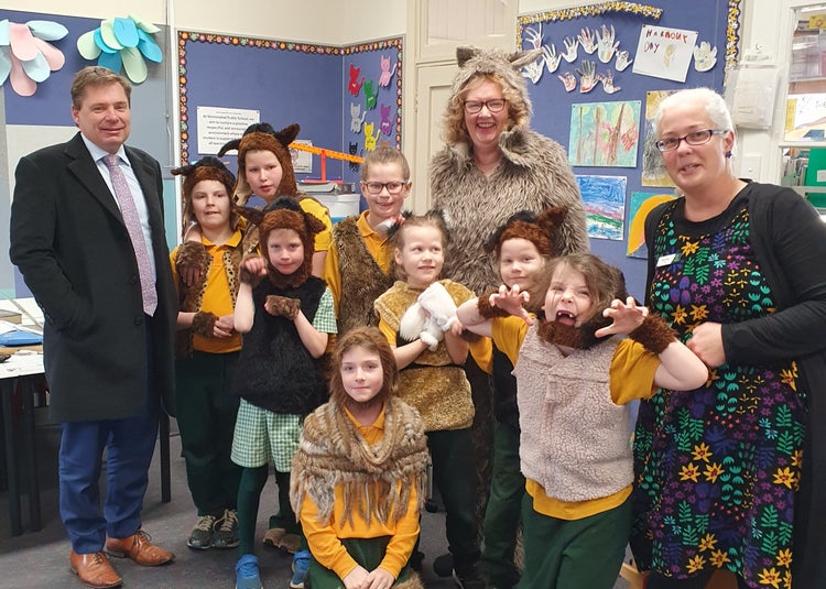 A photo of students and a teacher dress up as wolves, as well as the director in his suit and the school principal smiling to the side.