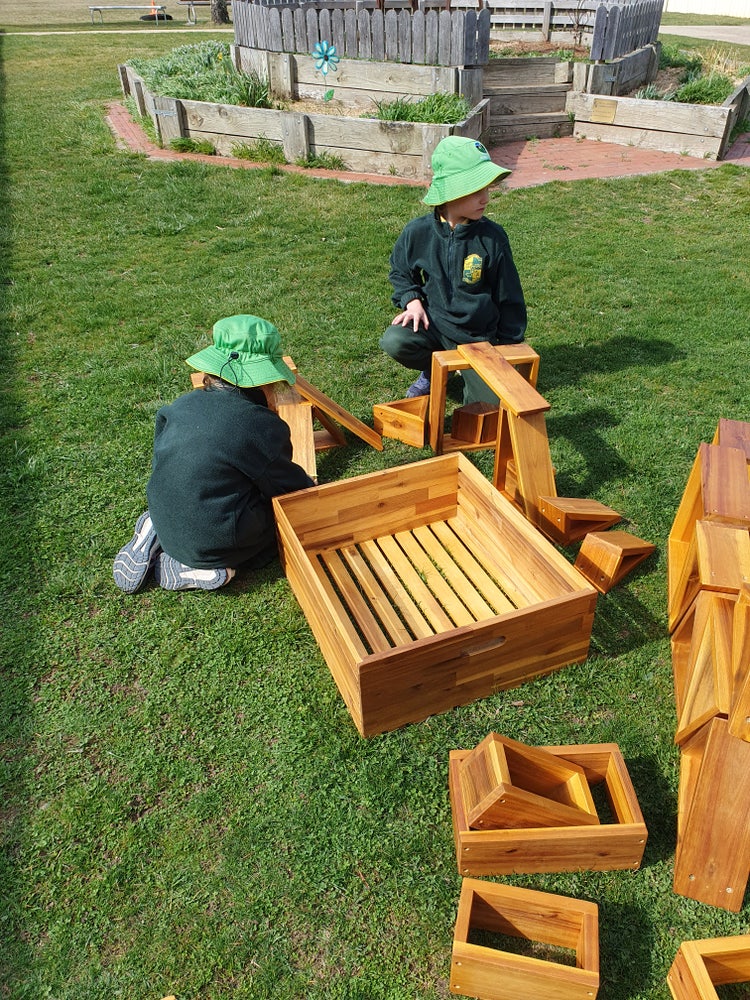 Two students playing with large wooden blocks making tracks and experimenting with building structures