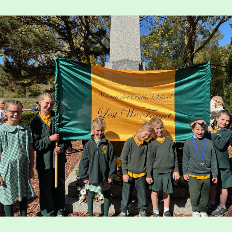 School students holding a 'Lest We Forget' banner at an ANZAC day service